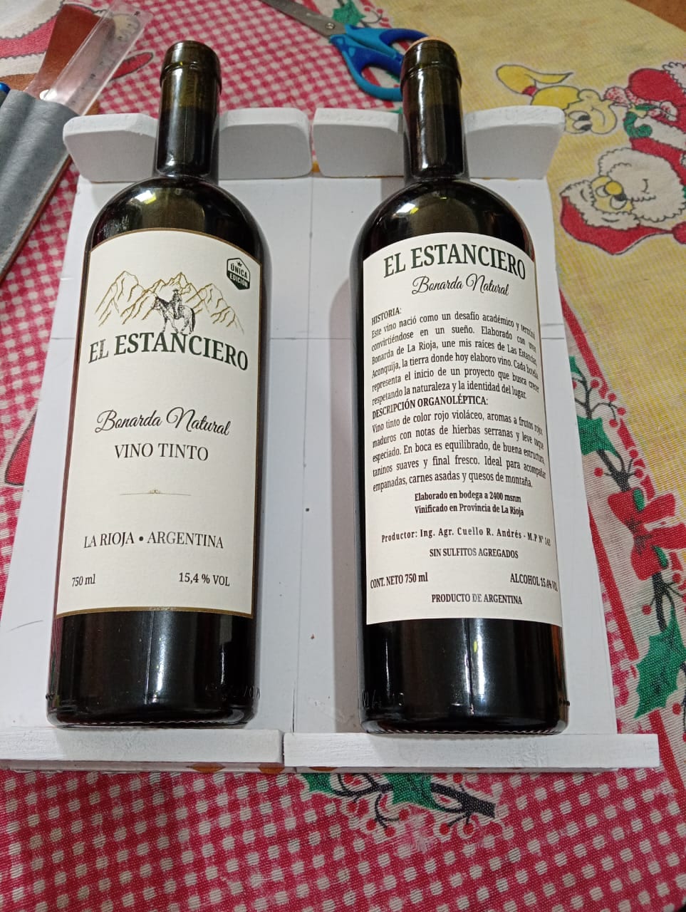 Las dos botellas terminadas de El Estanciero, de frente y de contraetiqueta, sobre un cajón de madera