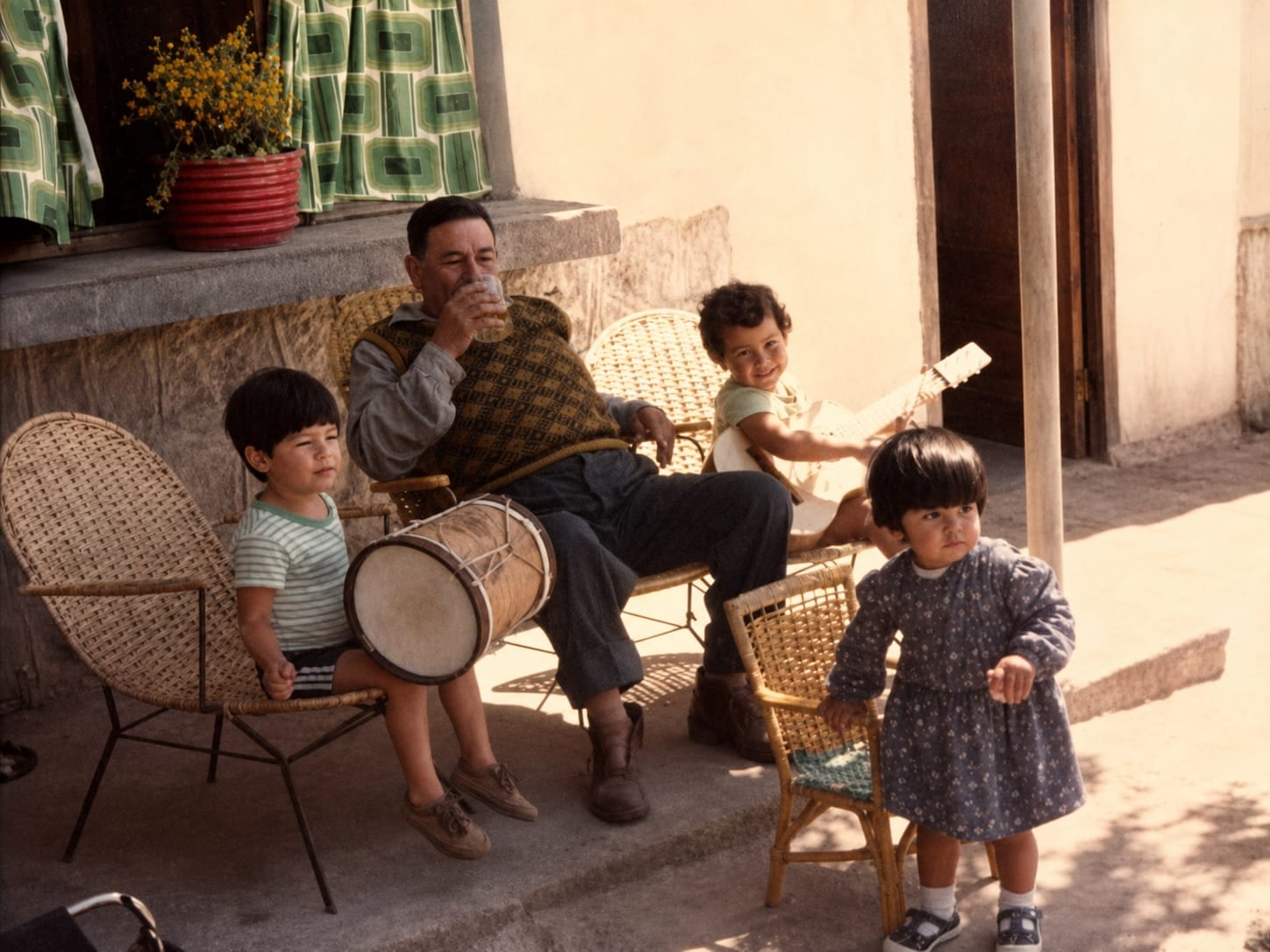 Fotografía original: el abuelo tomando algo en una silla de mimbre, rodeado de tres nietos, uno con un bombo y otro con una guitarra